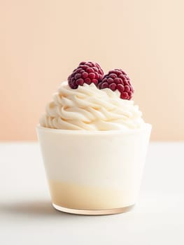 A cupcake with whipped cream and raspberries on top. The whipped cream is fluffy and the raspberries are frozen. The cupcake is sitting on a white table