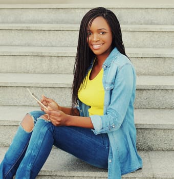 Beautiful young smiling african woman using tablet pc computer in the city