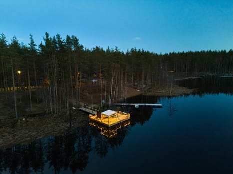 A charming, peaceful lakeside cabin, beautifully illuminated at twilight, nestled among the tranquil woods