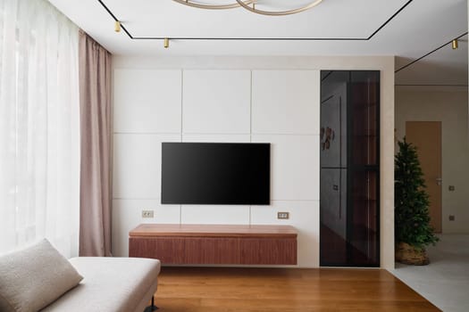 This modern living room features stylish decor, a contemporary TV unit, and plenty of natural light