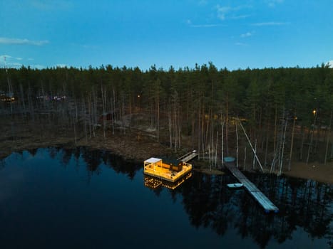 A serene and picturesque view of a charming lakeside cabin nestled amidst tall trees during the dusk hours