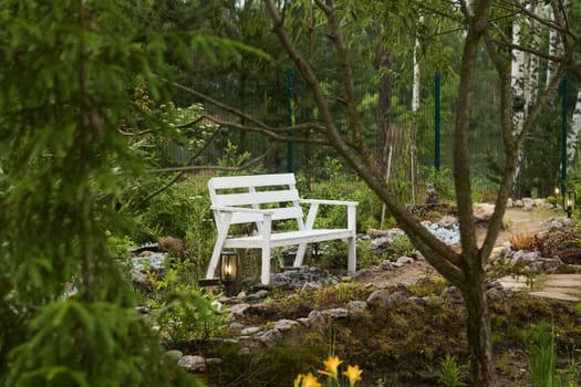 A serene and peaceful white bench gracefully nestled among lush green foliage and enchanting natural beauty