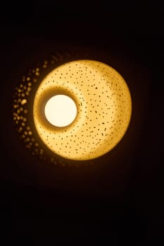 A stunning round light fixture that gracefully casts a warm, ambient glow across a dark setting, enhancing it