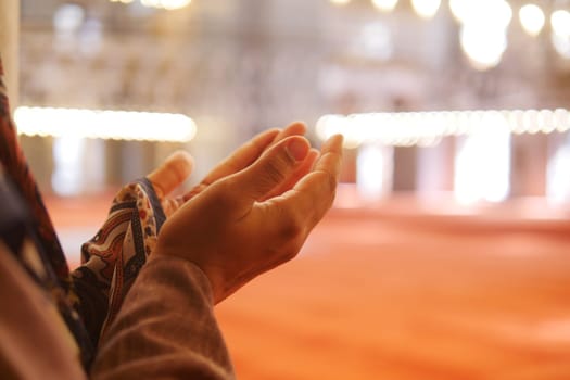 Muslim young woman in hijab is praying in mosque