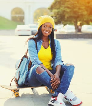Fashion happy smiling young african woman with skateboard in the city