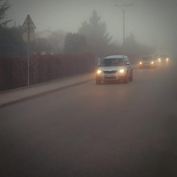 Car on the road in the fog. Autumn landscape - dangerous road traffic in winter season