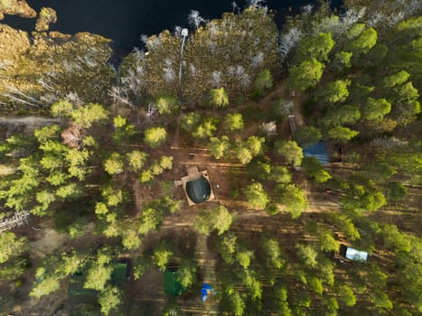 Aerial view of a tranquil forest retreat by a shimmering lake, surrounded by lush greenery and natural beauty