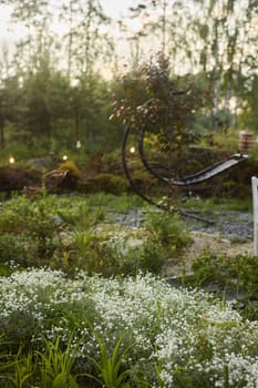 A tranquil and peaceful garden that magnificently showcases vibrant flowers and a unique artistic sculpture at sunset