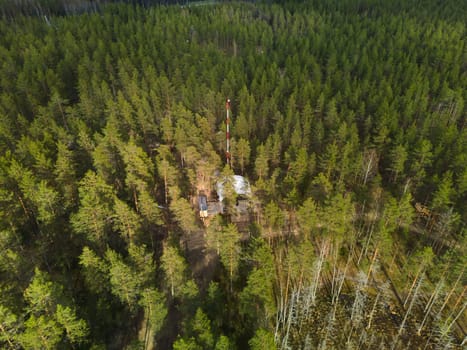 An aerial view of a lush forest showcasing a remote site equipped with various types of machinery and tools