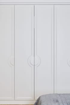 This modern wardrobe features sleek white doors with circular handles, combining elegance and functionality