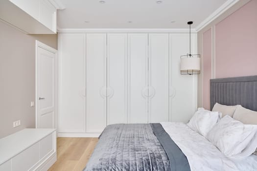 A tranquil and modern bedroom featuring a cozy bed, chic furnishings, and a soothing soft color palette