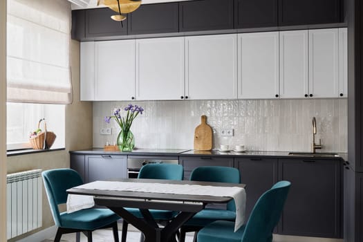 This stylish kitchen showcases beautiful white and black cabinetry, vibrant teal chairs, and lovely floral decor