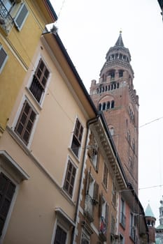 Cremona, Italy - November 20th 2024 The torrazzo bell tower of cremona cathedral rises above colorful buildings with wooden shutters in cremona, italy