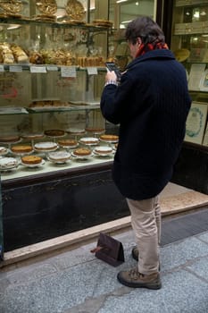 Cremona, Italy - November 20th 2024 Tourist taking pictures of traditional italian pastries displayed in a shop window in cremona, lombardy