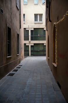 Cremona, Italy - November 20th 2024 Stone paved alley with christmas lights leading to a courtyard in the historic city center of cremona