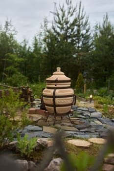 A serene and tranquil garden setting showcasing a traditional cooking pot surrounded by vibrant, lush greenery