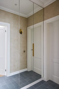 This chic hallway showcases stunning reflective walls, contemporary design elements, and sleek, modern details