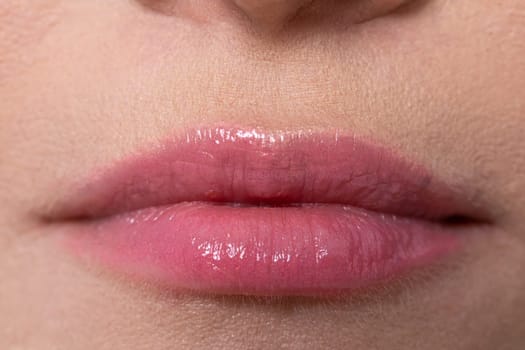 An alluring closeup photograph of beautifully glossed pink lips, showcasing a natural and fresh look that captivates