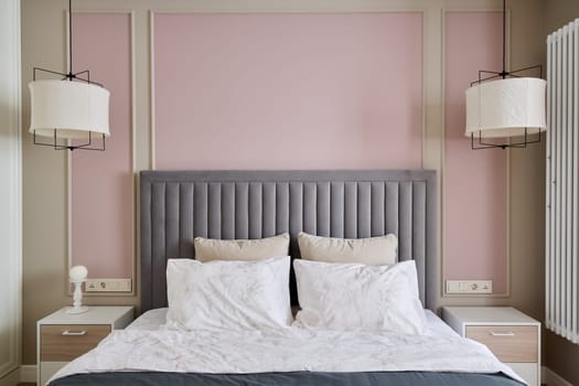 A chic and contemporary bedroom space that showcases a stylish gray upholstered headboard against soft pastel walls