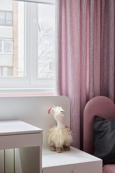 The cozy room has a charming llama plush toy by soft pink curtains and modern decor that enhance its aesthetic