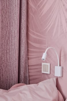 A stylish corner of a cozy bedroom showcasing elegant pink decor, chic curtains, and modern bedside lighting fixtures