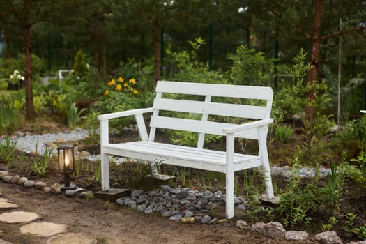 A pure white wooden bench sits elegantly in a tranquil garden, perfect for relaxation or contemplation