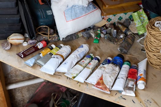 A vibrant set of paint tubes and essential tools is arranged on a neat workbench, ideal for artistic projects