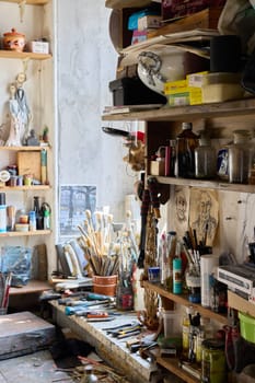 A vibrant artists studio, overflowing with artistic tools, colorful paints, and creative items everywhere