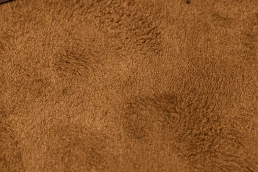 A detailed closeup of a soft and textured suede fabric in a warm, inviting brown hue, ideal for stylish upholstery