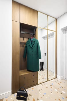 An elegant and welcoming entryway featuring a vibrant green coat, sleek cabinetry, and stylish decor elements