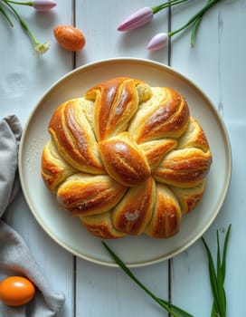 A beautifully shaped sweet bread sits on a plate, surrounded by spring flowers and decorative eggs. Natural light highlights the warm, golden crust, evoking a festive atmosphere.
