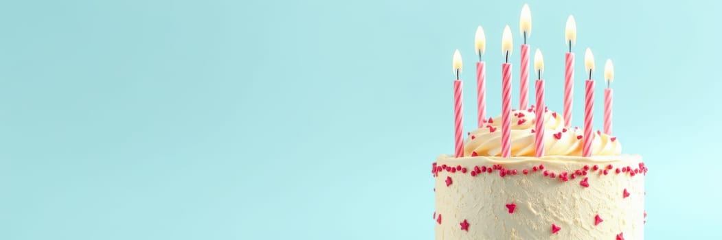 A beautifully designed birthday cake topped with colorful candles ready for a celebration. The light blue background enhances the festive atmosphere of the occasion.
