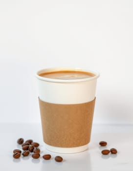 A disposable coffee cup filled with steaming hot coffee sits next to scattered coffee beans on a white surface, emphasizing the rich aroma of freshly brewed coffee.