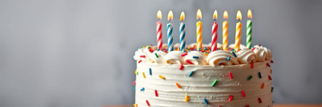 A festive birthday cake adorned with colorful sprinkles sits on a table, topped with eight lit candles. It represents celebration and joy during a special event.