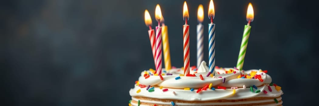 A round cake topped with white icing and colorful sprinkles holds eight lit candles, creating a warm glow in a softly illuminated room, perfect for a birthday or celebration.