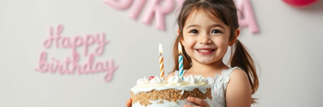 A young girl beams with joy as she holds a decorated birthday cake featuring lit candles. Colorful decorations and a happy birthday sign set a cheerful atmosphere.