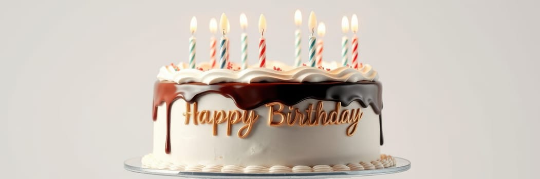 A beautifully decorated birthday cake sits on a glass stand, adorned with colorful candles. The cake features a delightful inscription and drizzles of chocolate, perfect for a celebration.