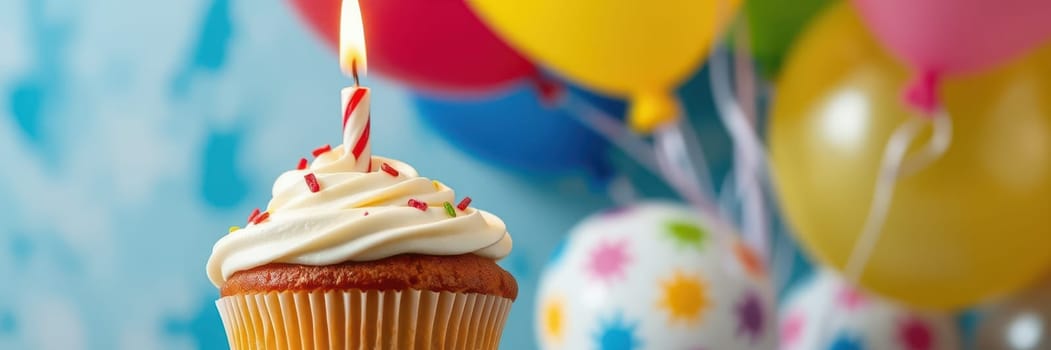 A cupcake topped with creamy frosting and a lit candle is featured prominently, surrounded by vibrant balloons in various colors, suggesting a joyful birthday party atmosphere.
