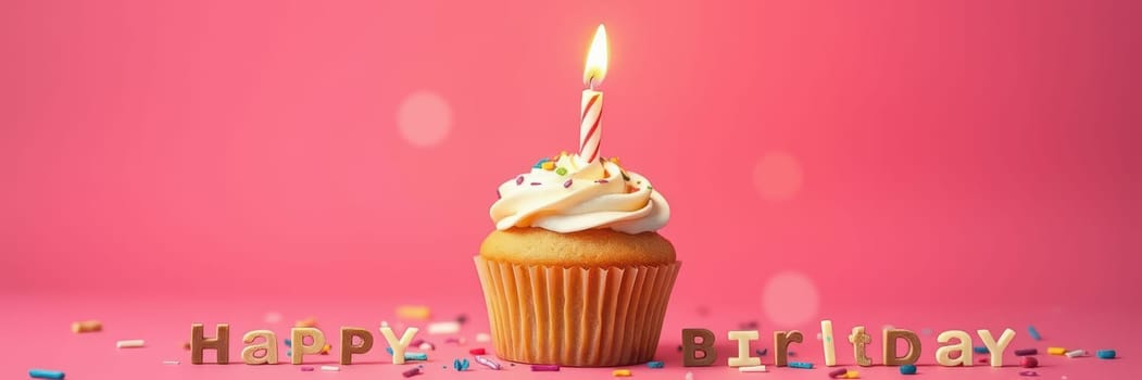 A delightful cupcake topped with buttercream frosting and a lit candle is surrounded by colorful sprinkles. The cheerful pink background enhances the festive atmosphere.
