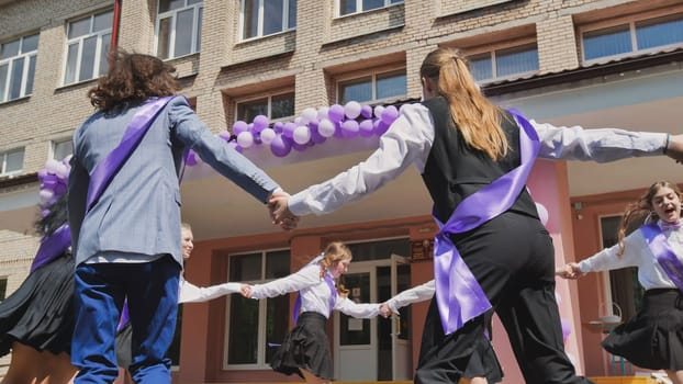 Graduates perform a traditional dance outside their school to mark the end of the school year and celebrate their graduation