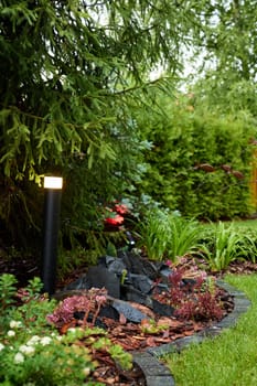 A beautiful garden scene that features exquisite landscaping, ambient lights, and vibrant, lush greenery all around