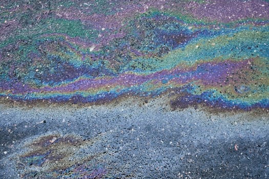 Vivid oil stain on an asphalt road, creating an abstract background.