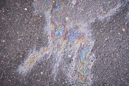 Circular patch of vibrant gasoline or oil spill on the roadway