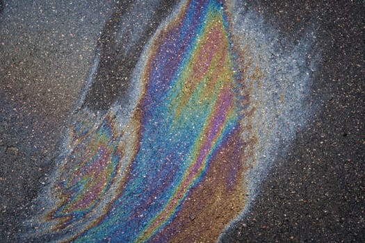 A multi-colored oil slick on an asphalt driveway that shimmers with all the colors of the rainbow