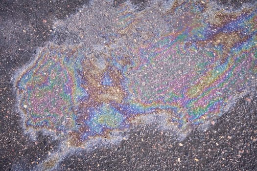 Eye-catching iridescent spot from oil or gasoline leakage on the asphalt.