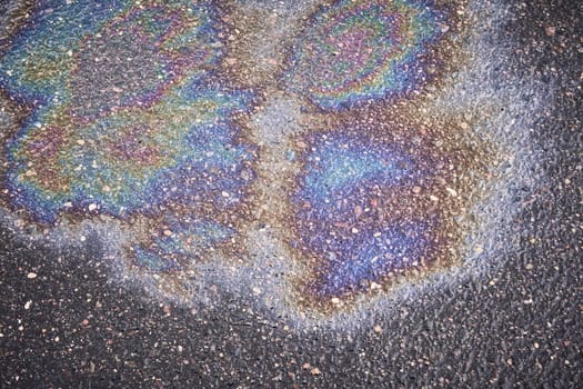 Colorful texture of gasoline stain on wet sidewalk
