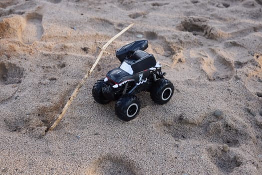 A sleek black remotecontrolled monster truck racing across sandy terrain, ideal for exhilarating outdoor adventures