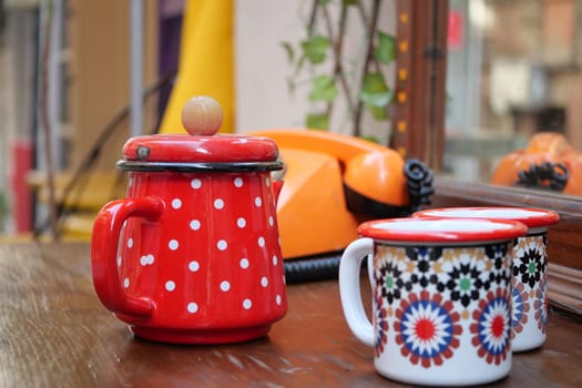 Charming kitchenware with a bright red jar and decorative mugs, perfect for dining