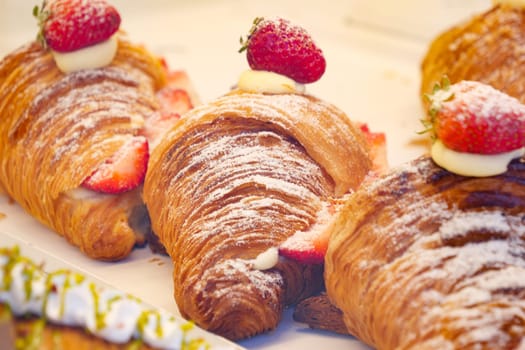 Indulge in freshly baked croissants that are beautifully adorned with ripe strawberries and cream