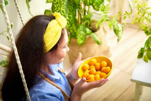 The gardener joyfully collects fresh fruits while enjoying the greenhouse's vibrant atmosphere.